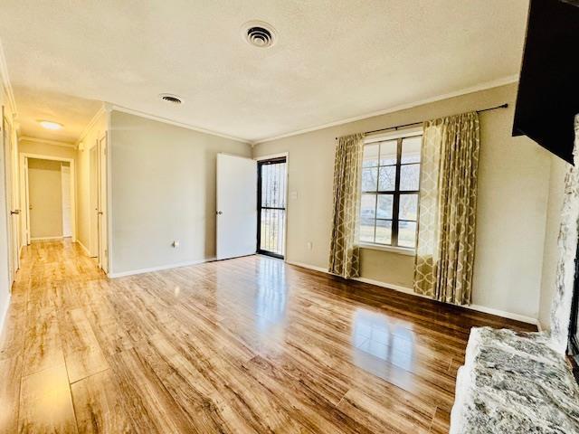 empty room featuring ornamental molding, a textured ceiling, and light wood-type flooring