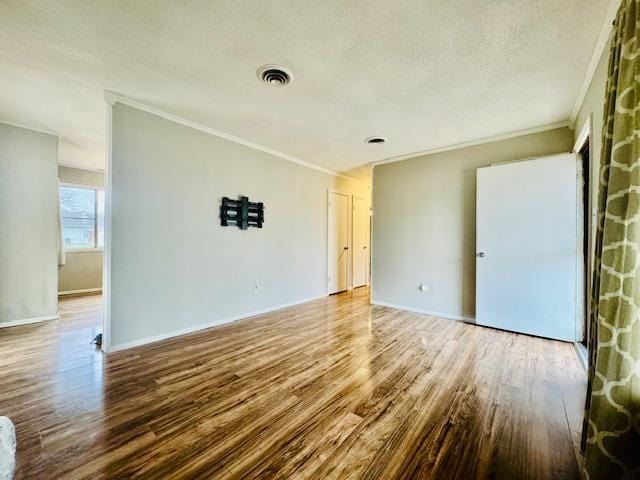 unfurnished room with crown molding, hardwood / wood-style flooring, and a textured ceiling