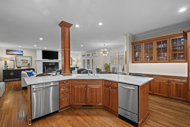 kitchen featuring stainless steel dishwasher, a center island, a tile fireplace, and ornate columns