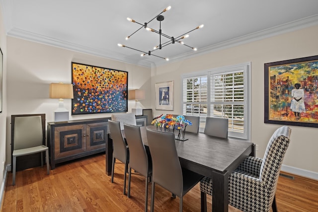 dining area featuring crown molding, a chandelier, and light hardwood / wood-style flooring