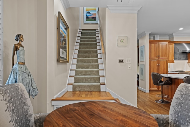 stairs featuring crown molding and hardwood / wood-style flooring