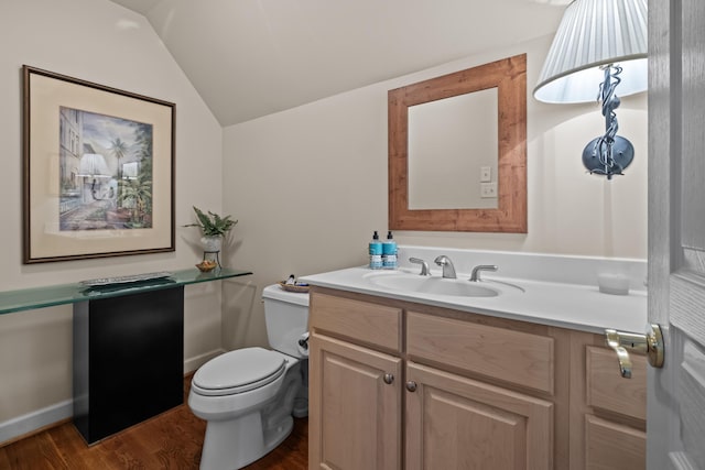 bathroom featuring vanity, lofted ceiling, wood-type flooring, and toilet