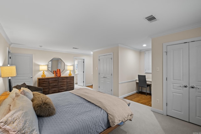 bedroom featuring crown molding, light carpet, and two closets