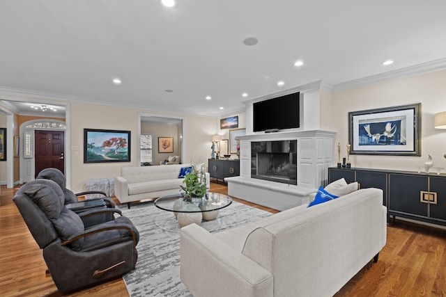 living room featuring hardwood / wood-style flooring, a tiled fireplace, and crown molding