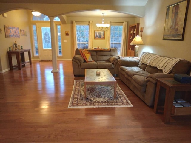 living room featuring ornate columns, a notable chandelier, and dark hardwood / wood-style flooring