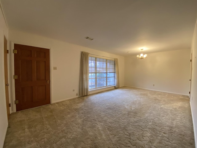 unfurnished room featuring a notable chandelier and carpet