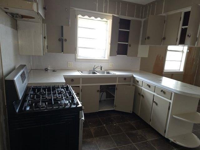 kitchen with tasteful backsplash, sink, stainless steel gas range, and white cabinets