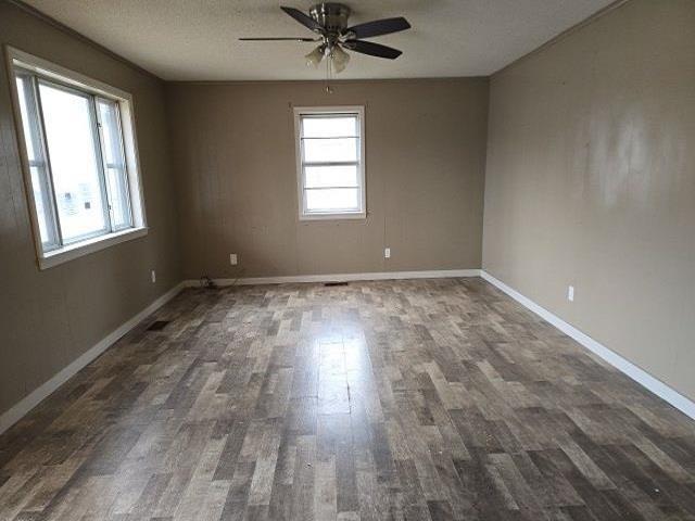 empty room with dark hardwood / wood-style flooring, ceiling fan, and a textured ceiling