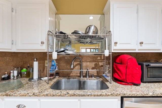 kitchen with dishwasher, white cabinetry, sink, and backsplash