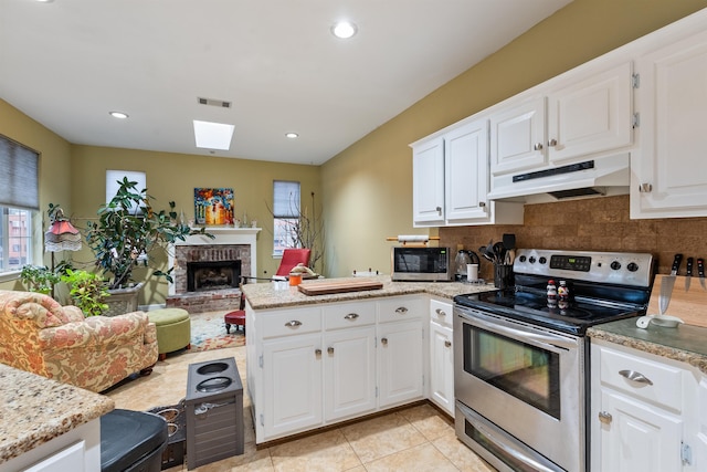 kitchen with appliances with stainless steel finishes, white cabinetry, tasteful backsplash, a fireplace, and kitchen peninsula