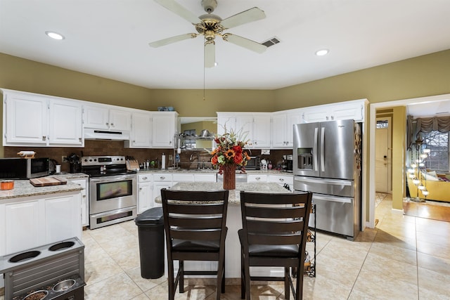 kitchen with white cabinetry, stainless steel appliances, light tile patterned flooring, and decorative backsplash