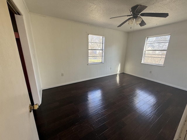 empty room featuring dark hardwood / wood-style flooring, a textured ceiling, and a wealth of natural light