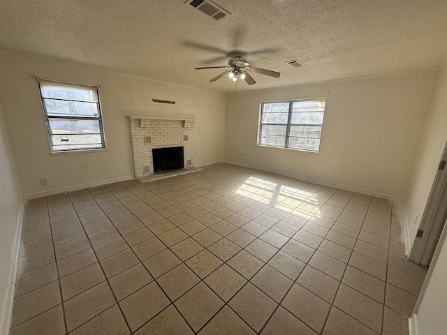 unfurnished living room with ceiling fan, light tile patterned floors, a brick fireplace, and a wealth of natural light