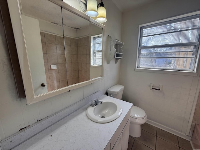 bathroom with tile patterned flooring, vanity, a wealth of natural light, and toilet