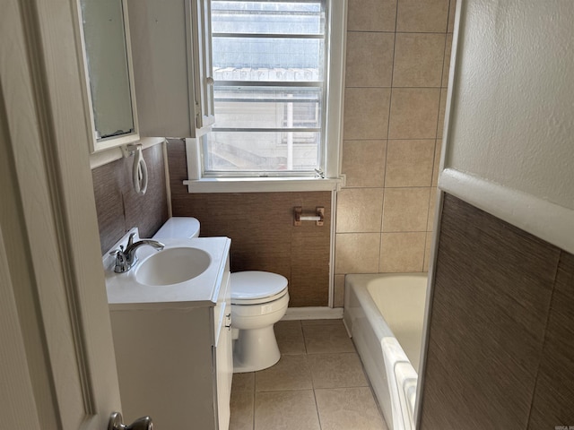 bathroom with tile patterned flooring, tile walls, vanity, toilet, and a bathing tub