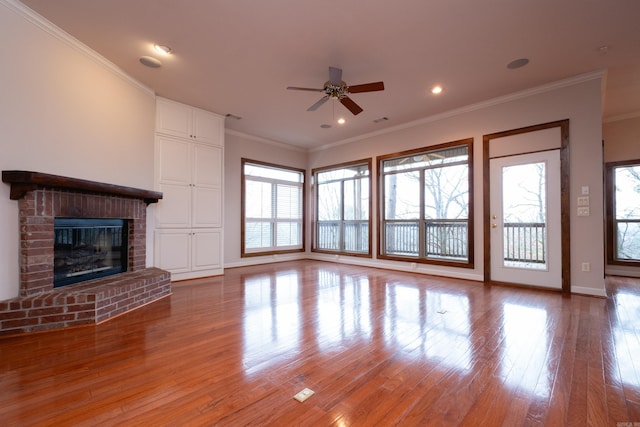 unfurnished living room featuring ceiling fan, ornamental molding, light hardwood / wood-style floors, and a brick fireplace