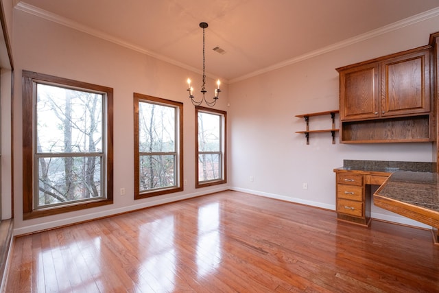 unfurnished dining area featuring crown molding, a chandelier, and hardwood / wood-style floors