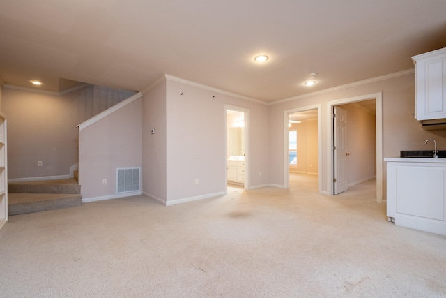 unfurnished living room with light carpet, sink, and crown molding