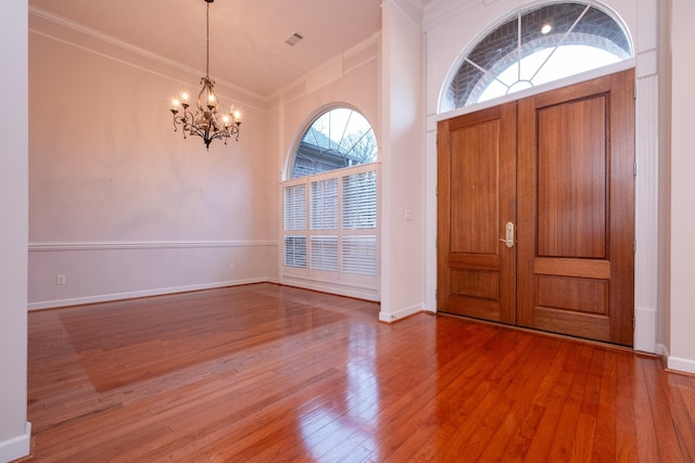 foyer featuring an inviting chandelier, ornamental molding, and hardwood / wood-style flooring