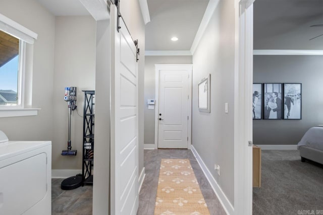 corridor with washer / clothes dryer, ornamental molding, and a barn door