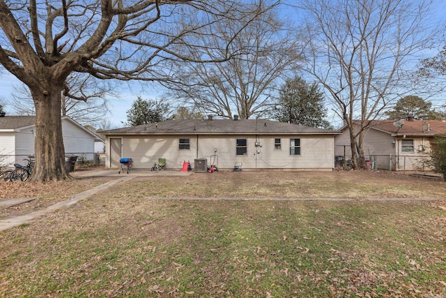 rear view of property featuring central AC unit and a lawn