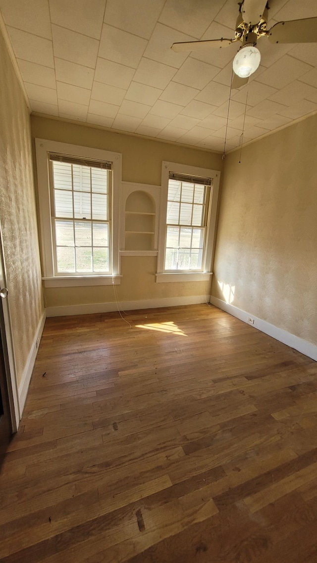 spare room featuring a ceiling fan, hardwood / wood-style flooring, and baseboards