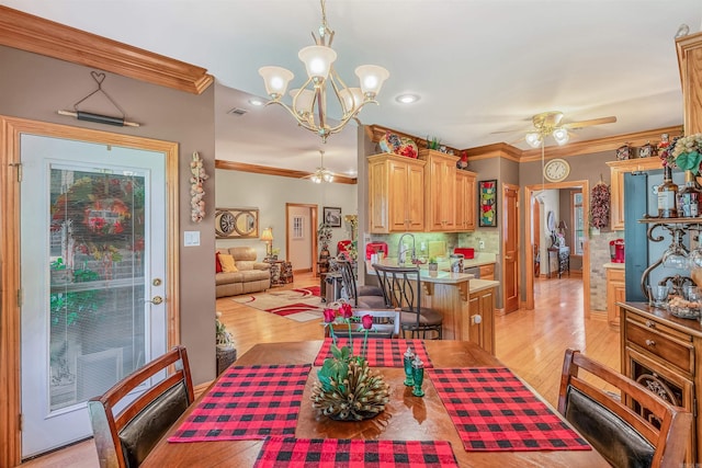 dining area featuring ceiling fan with notable chandelier, light hardwood / wood-style flooring, and ornamental molding