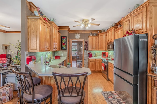 kitchen with a breakfast bar, sink, crown molding, kitchen peninsula, and stainless steel appliances