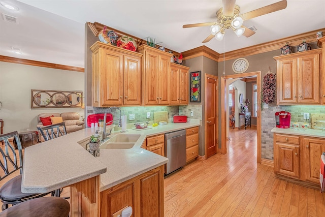 kitchen featuring sink, a kitchen breakfast bar, stainless steel dishwasher, kitchen peninsula, and crown molding