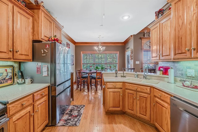 kitchen with sink, crown molding, light hardwood / wood-style flooring, appliances with stainless steel finishes, and decorative light fixtures