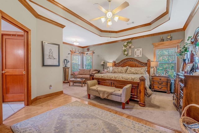 bedroom with a raised ceiling, ornamental molding, and light hardwood / wood-style floors