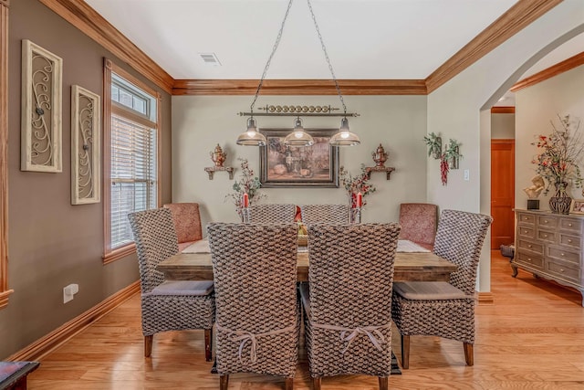 dining space with crown molding and light hardwood / wood-style floors