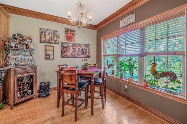 dining space featuring ornamental molding, a chandelier, and light hardwood / wood-style flooring