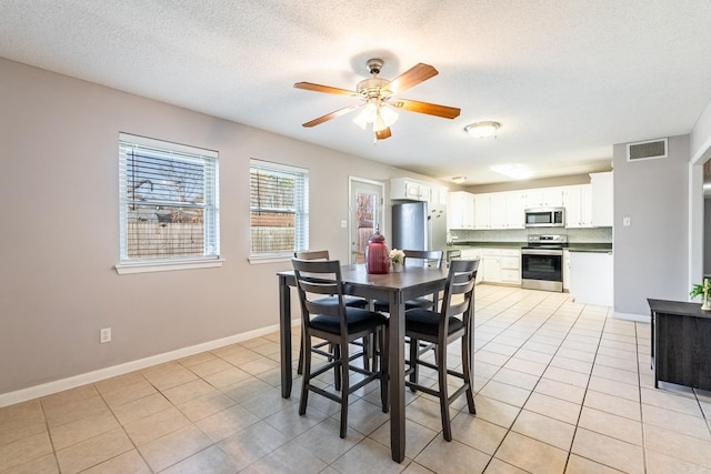 tiled dining room with ceiling fan and a textured ceiling