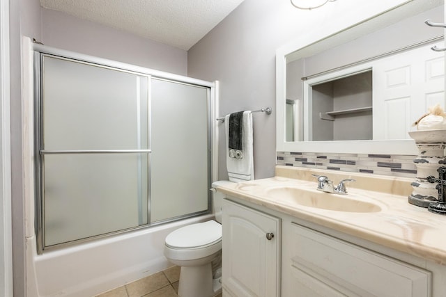 full bathroom with combined bath / shower with glass door, vanity, toilet, tile patterned floors, and a textured ceiling