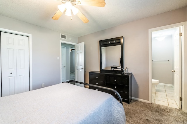 carpeted bedroom featuring ceiling fan, a textured ceiling, ensuite bath, and a closet