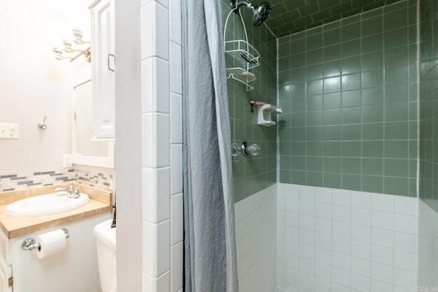 bathroom featuring vanity, backsplash, toilet, and tiled shower