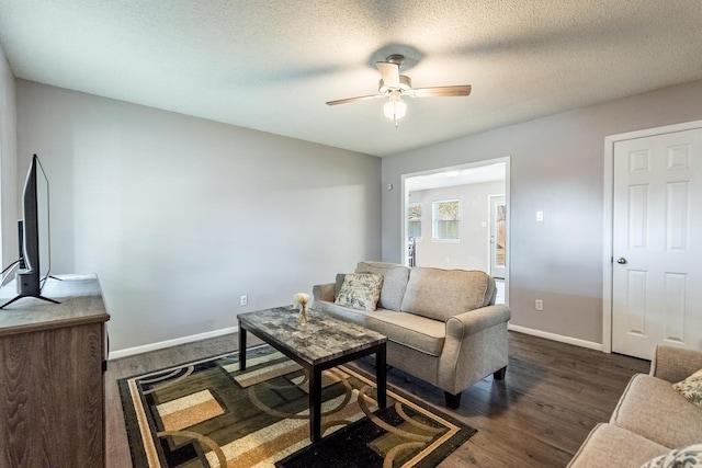 living room with dark hardwood / wood-style flooring, a textured ceiling, and ceiling fan