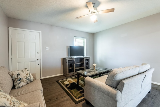 living room with a textured ceiling, dark wood-type flooring, and ceiling fan