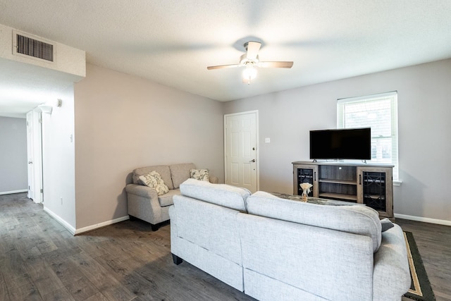 living room featuring dark wood-type flooring, a textured ceiling, and ceiling fan