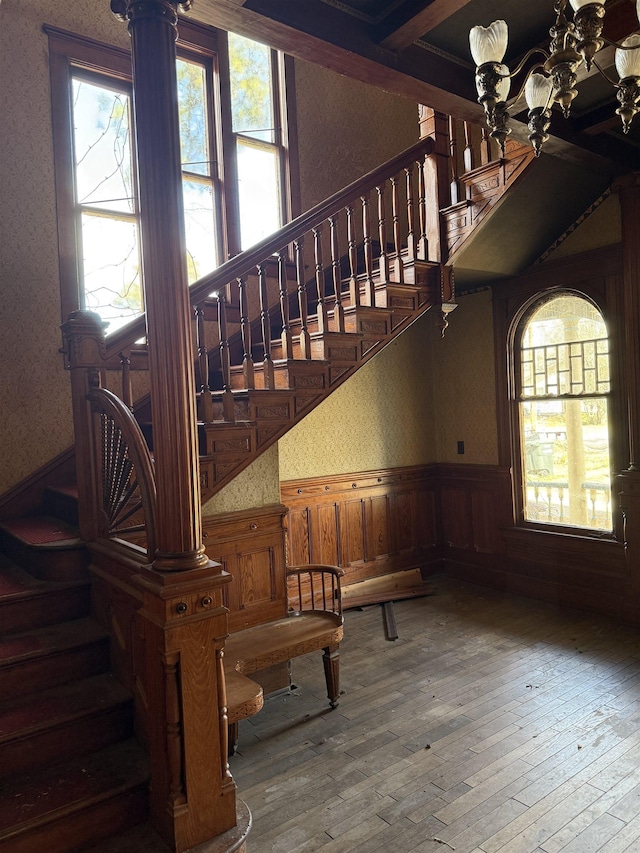 stairway with hardwood / wood-style floors and a chandelier