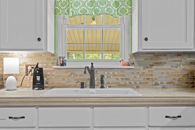 kitchen featuring sink, decorative backsplash, and white cabinets