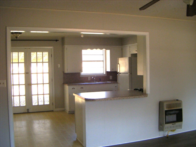 kitchen featuring sink, white cabinetry, white refrigerator, heating unit, and french doors