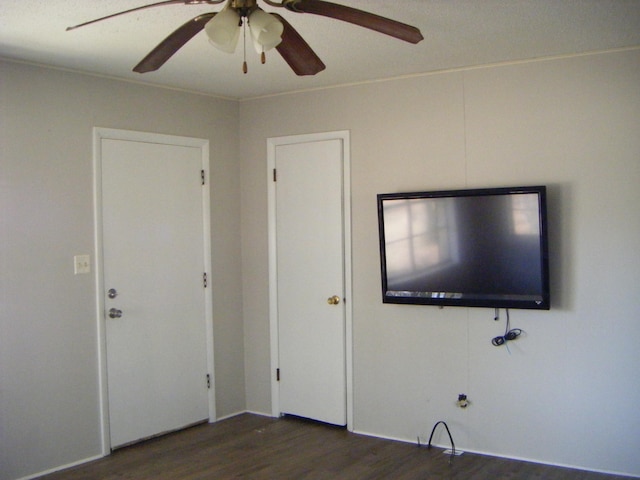 unfurnished living room featuring ceiling fan and dark hardwood / wood-style flooring