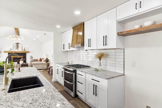 kitchen with double oven range, light stone countertops, and white cabinets