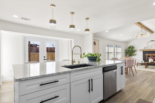 kitchen featuring pendant lighting, sink, light stone counters, and stainless steel dishwasher