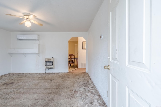 interior space with heating unit, a wall mounted air conditioner, light colored carpet, and ceiling fan