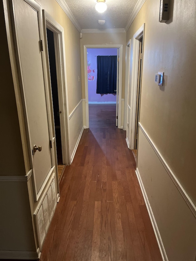 hall featuring dark wood-type flooring, ornamental molding, and a textured ceiling