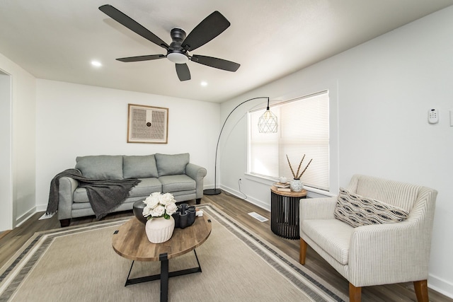 living room featuring dark wood-type flooring and ceiling fan