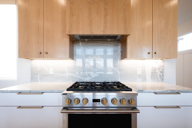 kitchen featuring light stone countertops, decorative backsplash, range hood, and gas stove